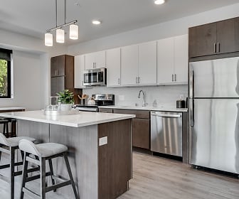 kitchen featuring a kitchen bar, natural light, stainless steel appliances, range oven, dark brown cabinetry, light countertops, light hardwood floors, and pendant lighting, Parker Station Flats