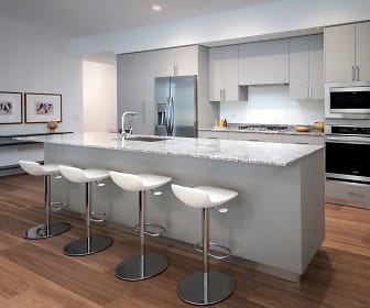 kitchen with a breakfast bar, stainless steel appliances, gas cooktop, light stone countertops, light parquet floors, and white cabinets, Optima Kierland Apartments