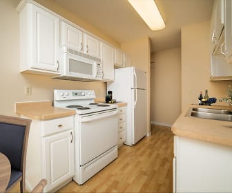 kitchen with refrigerator, electric range oven, microwave, light hardwood floors, white cabinets, and light countertops, Chesterwood Apartments