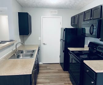 kitchen with refrigerator, electric range oven, microwave, light granite-like countertops, dark brown cabinets, and dark hardwood flooring, The Gardens Apartments