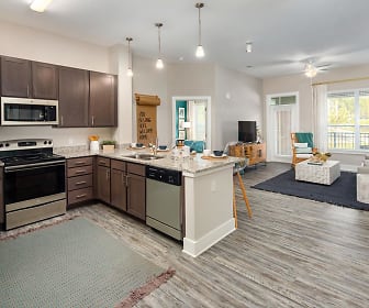 kitchen featuring a ceiling fan, a center island, natural light, stainless steel microwave, electric range oven, TV, dishwasher, pendant lighting, light granite-like countertops, dark brown cabinets, and light hardwood floors, Abberly Solaire
