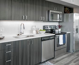 kitchen featuring stainless steel appliances, electric range oven, light hardwood floors, dark brown cabinetry, and light countertops, Sanctuary