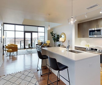 kitchen featuring a center island, natural light, a kitchen breakfast bar, electric range oven, stainless steel microwave, dark brown cabinetry, pendant lighting, light parquet floors, and light countertops, Steele Creek Apartments