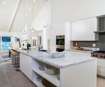 kitchen featuring a center island, natural light, gas cooktop, double oven, exhaust hood, pendant lighting, white cabinetry, light stone countertops, and light parquet floors, The Cove At Tiburon