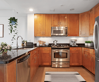 kitchen featuring stainless steel appliances, range oven, light floors, brown cabinets, and dark stone countertops, Juliana Luxury Apartments