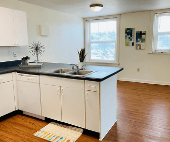 kitchen featuring plenty of natural light, dishwasher, dark countertops, light parquet floors, and white cabinets, Le Claire Apartments