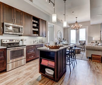 kitchen with a notable chandelier, natural light, a kitchen island, refrigerator, electric range oven, stainless steel microwave, dark brown cabinetry, pendant lighting, light parquet floors, and light countertops, The Kathryn