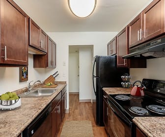kitchen featuring electric range oven, ventilation hood, dishwasher, light hardwood flooring, light granite-like countertops, and dark brown cabinets, The Meadows