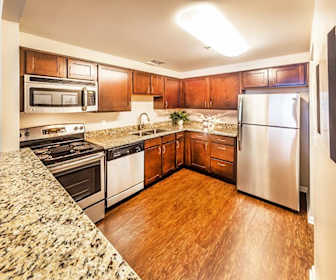 kitchen featuring electric range oven, stainless steel appliances, dark stone countertops, dark brown cabinets, and light parquet floors, Grandin House