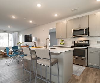 kitchen featuring natural light, stainless steel microwave, TV, electric range oven, kitchen island sink, light hardwood floors, light countertops, and white cabinetry, Woodmont Way at West Windsor