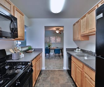 kitchen with refrigerator, dishwasher, microwave, dark granite-like countertops, dark tile floors, and brown cabinetry, Cedar Gardens & Towers Apartments & Townhomes