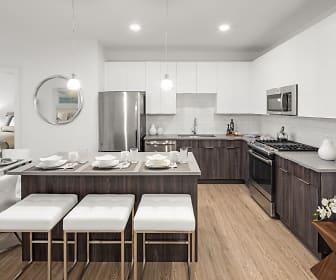 kitchen with a kitchen bar, gas range oven, stainless steel refrigerator, dishwasher, microwave, white cabinets, light countertops, pendant lighting, and light parquet floors, Harbor Landing at Garvies Point