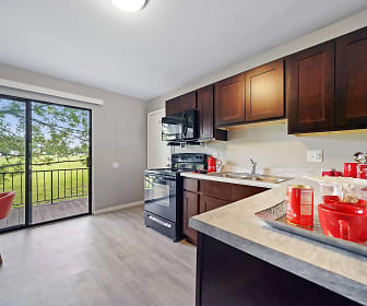 kitchen with a wealth of natural light, electric range oven, microwave, dark brown cabinetry, light countertops, and light hardwood flooring, The Flats at Gladstone