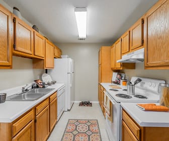 kitchen with electric range oven, refrigerator, dishwasher, fume extractor, light tile flooring, light countertops, and brown cabinetry, The Traditions At Augusta