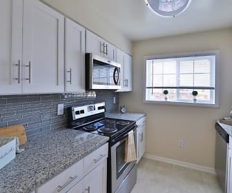 kitchen featuring natural light, stainless steel microwave, refrigerator, electric range oven, dishwasher, white cabinetry, light granite-like countertops, and light tile flooring, The Meadows