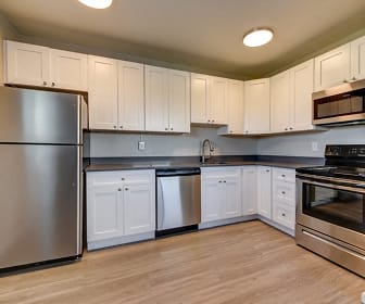 kitchen with stainless steel appliances, electric range oven, dark countertops, light parquet floors, and white cabinets, Lamar Station Apartments