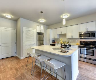 kitchen featuring a kitchen bar, stainless steel appliances, range oven, white cabinets, light countertops, pendant lighting, and light hardwood flooring, The Madison Bellevue