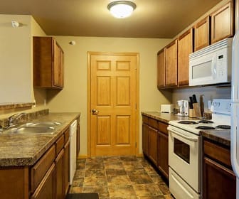 kitchen with refrigerator, dishwasher, electric range oven, microwave, dark tile flooring, dark granite-like countertops, and brown cabinetry, Tioga Square Apartments