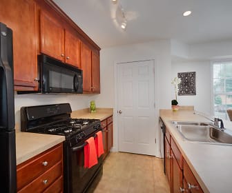 kitchen featuring natural light, gas range oven, refrigerator, microwave, light countertops, light tile floors, and brown cabinets, Park at Arlington Ridge