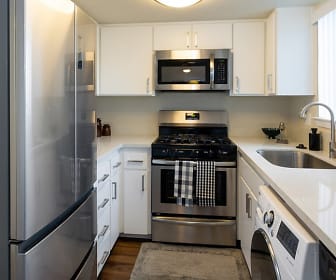 kitchen with stainless steel appliances, washer / dryer, gas range oven, white cabinetry, light floors, and light stone countertops, ReNew Park Blu