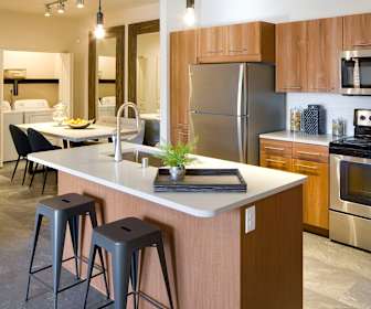 kitchen featuring electric range oven, stainless steel appliances, dark flooring, light countertops, pendant lighting, and brown cabinetry, Olympus Alameda