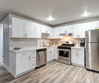 kitchen with natural light, gas range oven, stainless steel appliances, fume extractor, white cabinets, light countertops, and light hardwood flooring, Timbre Apartments