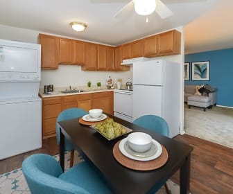 kitchen with a ceiling fan, ventilation hood, washer / dryer, refrigerator, range oven, light countertops, brown cabinetry, and light parquet floors, Mapleton Square Apartment Homes