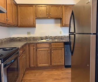 kitchen featuring electric range oven, stainless steel refrigerator, dishwasher, fume extractor, light hardwood flooring, dark granite-like countertops, and brown cabinetry, Heather Downs Apartments