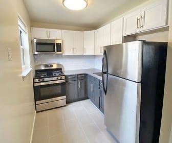 kitchen featuring gas range oven, refrigerator, stainless steel microwave, light countertops, white cabinetry, and light tile floors, Kennedy Gardens Apartments