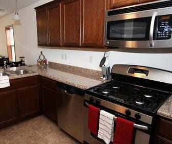 kitchen with stainless steel appliances, gas range oven, pendant lighting, light tile flooring, light granite-like countertops, and dark brown cabinets, Tioga Townhomes