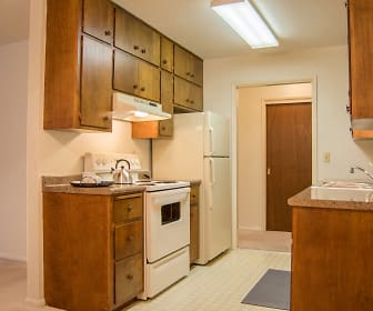 kitchen with ventilation hood, refrigerator, electric range oven, light floors, dark stone countertops, and brown cabinetry, University Square