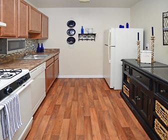 kitchen featuring ventilation hood, gas range oven, dishwasher, refrigerator, microwave, dark brown cabinetry, dark stone countertops, and light hardwood flooring, Willow Lake Apartment Homes