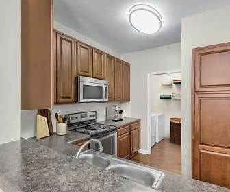 kitchen featuring electric range oven, stainless steel microwave, granite-like countertops, light parquet floors, and brown cabinets, Camden Stonecrest