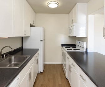 kitchen featuring refrigerator, electric range oven, microwave, dark granite-like countertops, white cabinetry, and light parquet floors, 55 West Fifth Apartments