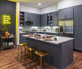 kitchen featuring a kitchen bar, stainless steel refrigerator, microwave, dark parquet floors, light countertops, and dark brown cabinets, The Braden on Fifth