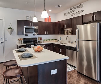 kitchen featuring a kitchen bar, stainless steel appliances, range oven, dark brown cabinetry, light countertops, pendant lighting, and dark hardwood floors, The Kane Apartment Homes