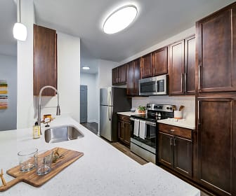 kitchen featuring carpet, electric range oven, stainless steel appliances, dark brown cabinets, light granite-like countertops, and pendant lighting, Aventura Crossroads