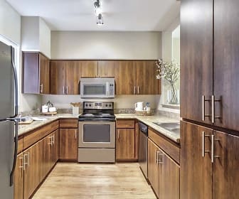 kitchen with refrigerator, electric range oven, dishwasher, microwave, light parquet floors, light granite-like countertops, and brown cabinetry, Camden Montierra