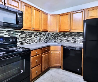 kitchen featuring electric range oven, refrigerator, dishwasher, stainless steel microwave, dark countertops, light hardwood flooring, and brown cabinets, Towson Crossing Apartment Homes