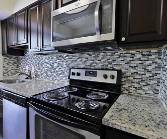 kitchen featuring electric range oven, dishwasher, stainless steel microwave, granite-like countertops, dark flooring, and dark brown cabinets, Villages At Montpelier Apartment Homes