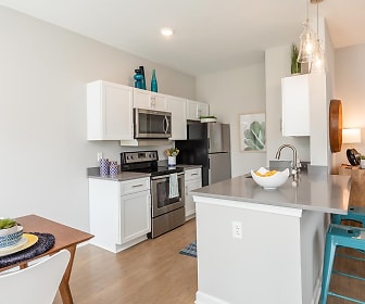 kitchen featuring refrigerator, electric range oven, stainless steel microwave, dark countertops, light hardwood flooring, pendant lighting, and white cabinets, Morgan Woodland Acres Townhomes