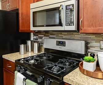 kitchen with refrigerator, gas range oven, microwave, light stone countertops, and brown cabinetry, Sherry Lake Apartments