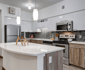kitchen with a kitchen island, stainless steel microwave, refrigerator, electric range oven, dishwasher, white cabinetry, light countertops, pendant lighting, and light hardwood flooring, Tessera Apartments
