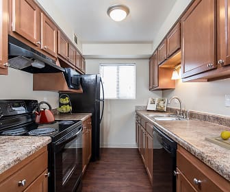 kitchen with natural light, refrigerator, electric range oven, dishwasher, exhaust hood, brown cabinetry, light stone countertops, and dark hardwood floors, Crossroads Apartments