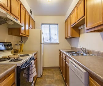 kitchen with natural light, electric range oven, dishwasher, extractor fan, light countertops, dark tile floors, and brown cabinetry, Crossroads Apartments