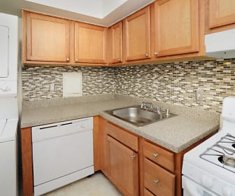 kitchen featuring washer / dryer, dishwasher, exhaust hood, light countertops, light tile floors, and brown cabinetry, Arbors at Edenbridge Apartment Homes