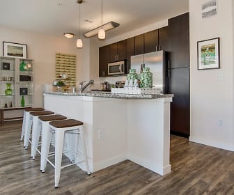 kitchen with a kitchen bar, stainless steel microwave, stone countertops, pendant lighting, dark brown cabinets, and light hardwood flooring, Westlink at Oak Station