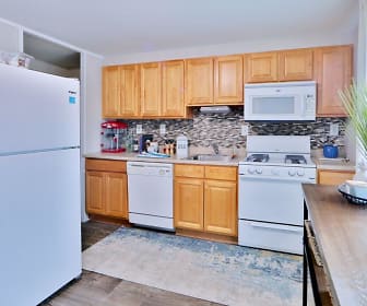 kitchen with refrigerator, gas range oven, dishwasher, microwave, light parquet floors, light countertops, and brown cabinetry, Gwynnbrook Townhomes