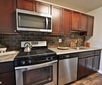 kitchen with gas range oven, stainless steel appliances, light hardwood floors, dark brown cabinets, and light granite-like countertops, Cedar Creek Apartment Homes