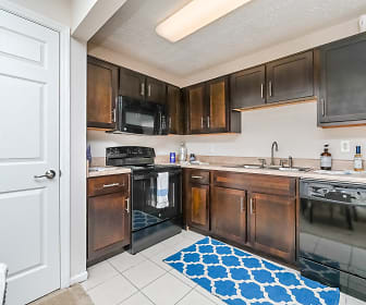 kitchen with dishwasher, electric range oven, microwave, light tile floors, dark brown cabinetry, and light granite-like countertops, The Park at Lake Magdalene
